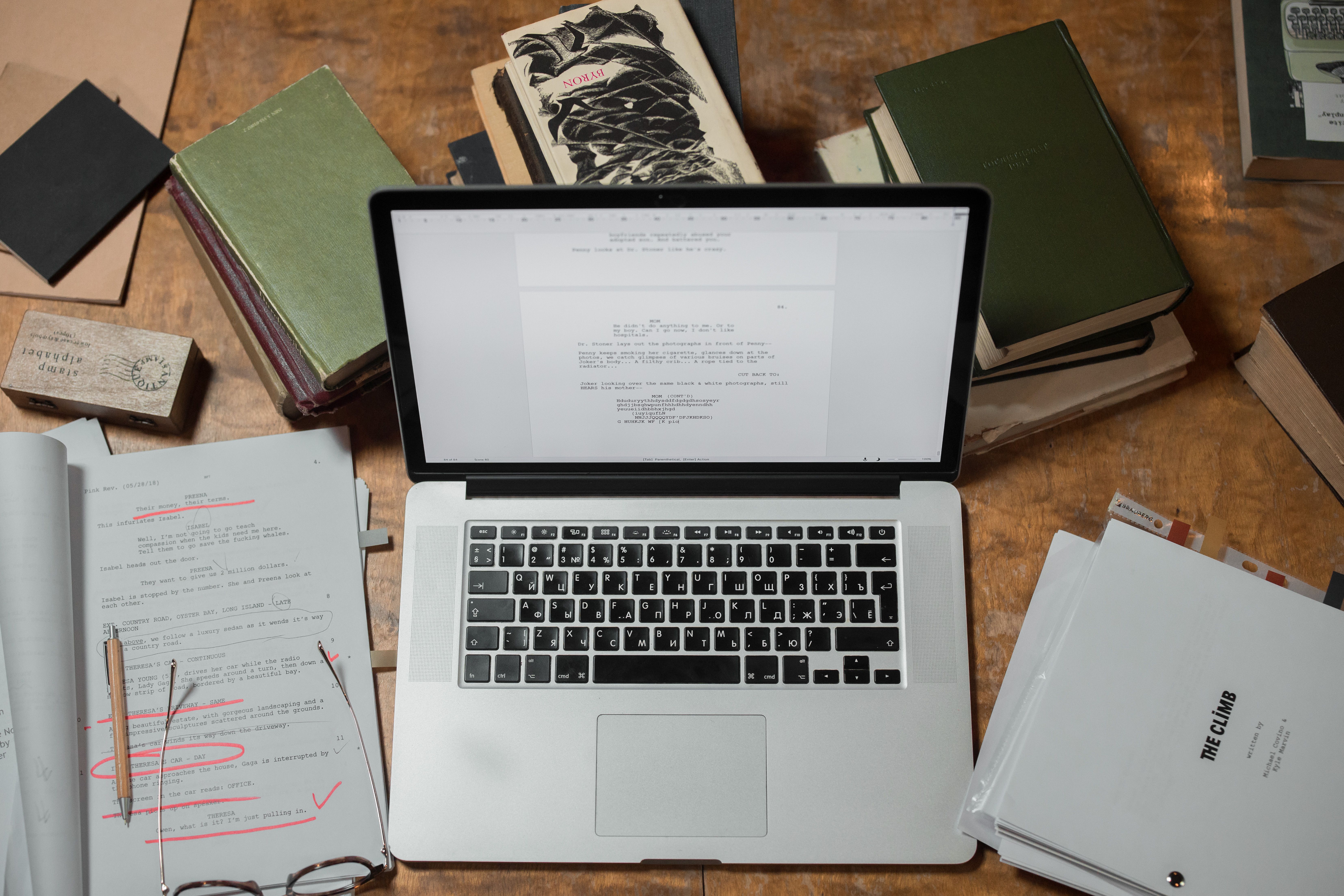 Laptop and books on a desk representing writing, editing, and digital grammar tools